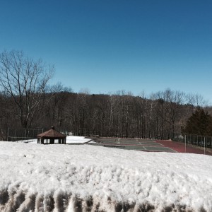 Tennis courts at CGCC still partially covered with snow. Big pile in foreground is from parking lot.